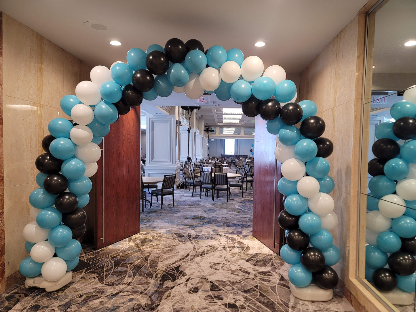 blue white and black balloons built into an archway in front of doors
